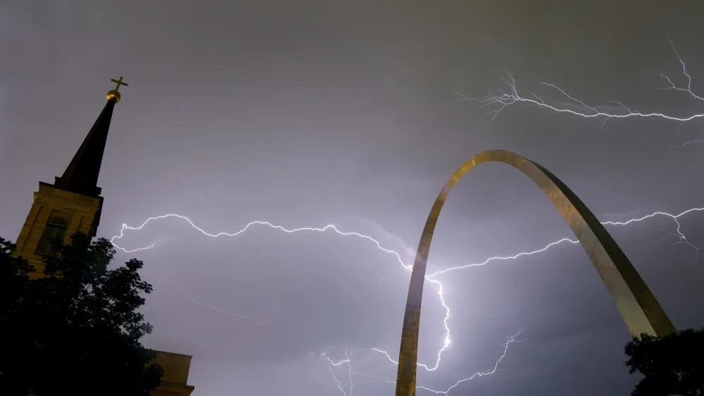 Lightning flashes in the sky behind the Gateway Arch, right, and Old Cathedral, left, as a line of thunderstorms moves through St. Louis, Wednesday, May 11, 2016. Thousands of Ameren Corp. customers in the St. Louis area are without power after the strong thunderstorm hit the region. (AP Photo/Jeff Roberson)