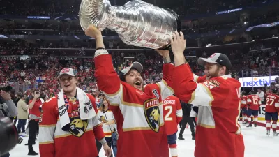 Florida Panthers defenseman Brandon Montour, center, lifts the Stanley Cup trophy after Game 7 of the NHL hockey Stanley Cup Final against the Edmonton Oilers, Monday, June 24, 2024, in Sunrise, Fla. The Panthers defeated the Oilers 2-1. (AP Photo/Wilfredo Lee)