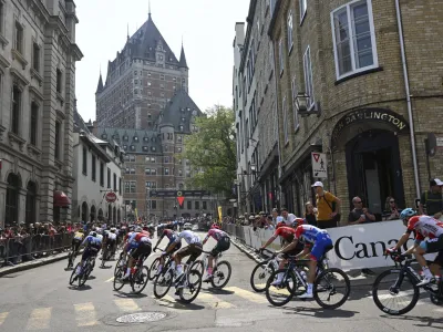 The main pack cycles up toward the Chateau Frontenac during the Grand Prix Cycliste de Quebec bicycle race, Friday, Sept. 9, 2022, in Quebec City, Canada. (Jacques Boissinot/The Canadian Press via AP)