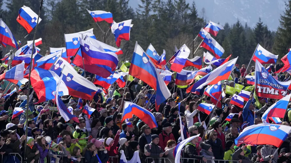 Fans wave Slovenian flags during the Men Flying Hill Individual competition at the FIS Ski Jumping World Cup in Planica, Slovenia, Sunday, March 27, 2022. (AP Photo/Darko Bandic)