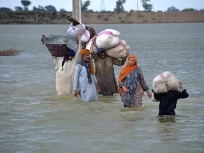 FILE - A displaced family wades through a flooded area after heavy rainfall, in Jaffarabad, a district of Pakistan's southwestern Baluchistan province, Aug. 24, 2022. A new study says human-caused climate change juiced the rainfall that triggered Pakistan's floods by up to 50%. But the authors of the Thursday, Sept. 15, study say other societal issues that make the country vulnerable and put people in harm's way are probably the biggest factor in the ongoing humanitarian disaster. (AP Photo/Zahid Hussain, File)