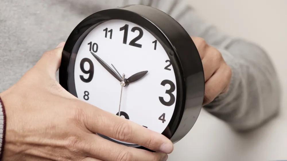 closeup of a young caucasian man adjusting the time of a clock