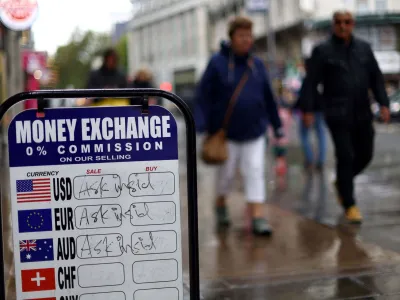 People walk past signage outside a currency exchange office in London, Britain, September 27, 2022. REUTERS/Hannah McKay