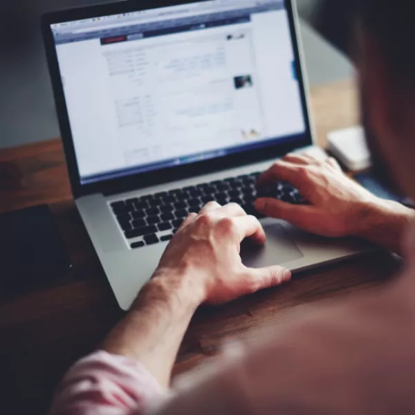 Cropped image of a young man working on his laptop in a coffee shop, rear view of business man hands busy using laptop at office desk, young male student typing on computer sitting at wooden table