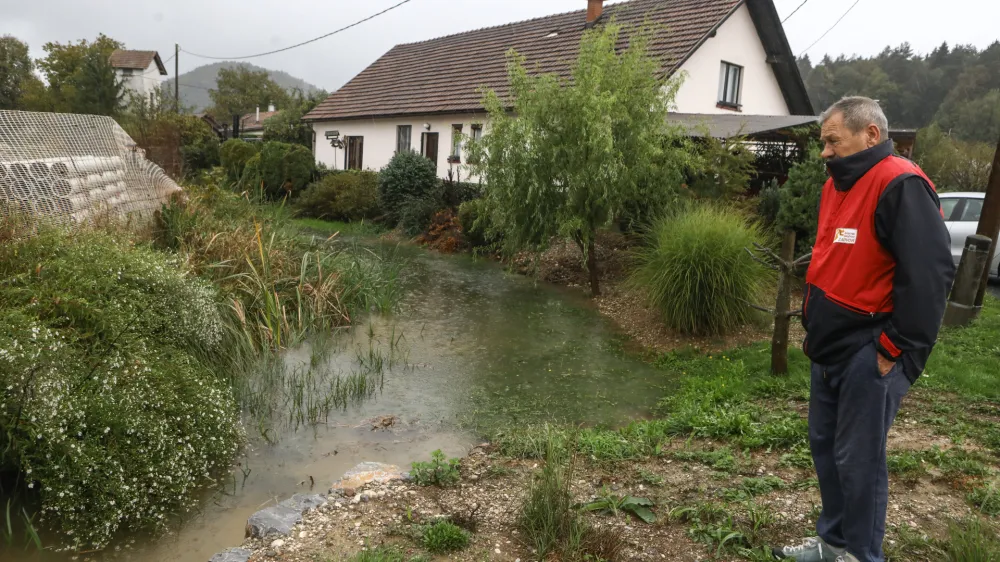 Visoka voda iz sicer nizkega potočka že spodjeda hišo družine Golouh v Sostrem. Foto: Luka Cjuha