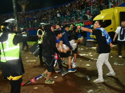 Supporters evacuate a man due to tear gas fired by police during the riot after the football match between Arema vs Persebaya at Kanjuruhan Stadium, Malang, East Java province, Indonesia, October 2, 2022. REUTERS/Stringer NO RESALES. NO ARCHIVES