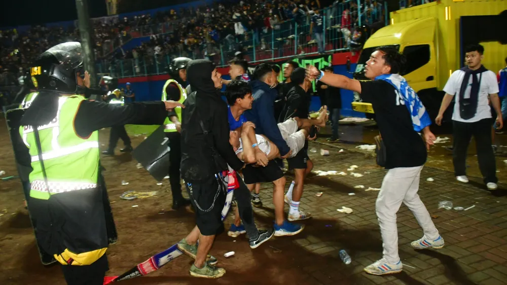 Supporters evacuate a man due to tear gas fired by police during the riot after the football match between Arema vs Persebaya at Kanjuruhan Stadium, Malang, East Java province, Indonesia, October 2, 2022. REUTERS/Stringer NO RESALES. NO ARCHIVES