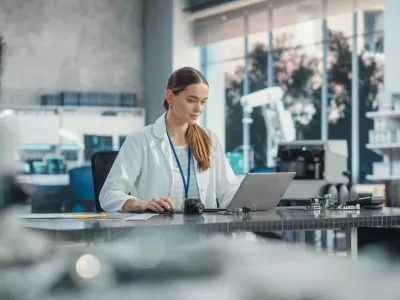 Portrait of Professional Female Scientist Working in Industrial Lab Using Laptop Computer. Successful Project Manager Making Strategy Plans for Industrial Production Company, Using Technology