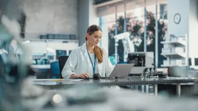 Portrait of Professional Female Scientist Working in Industrial Lab Using Laptop Computer. Successful Project Manager Making Strategy Plans for Industrial Production Company, Using Technology