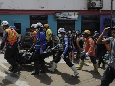 10 October 2022, Venezuela, Las Tejerias: Search and rescue workers carry the lifeless body of a woman after floods and a landslide caused by the storm 'Julia'. According to official figures, a total of at least 59 people died in Central and South America as a result of storms and floods. Photo: Jesus Vargas/dpa