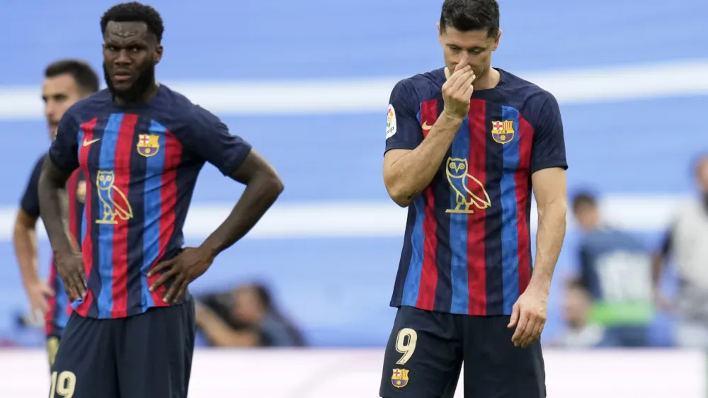 Barcelona's Robert Lewandowski, right, and Franck Kessie react during a Spanish La Liga soccer match between Real Madrid and Barcelona at the Santiago Bernabeu stadium in Madrid, Sunday, Oct. 16, 2022. (AP Photo/Manu Fernandez)