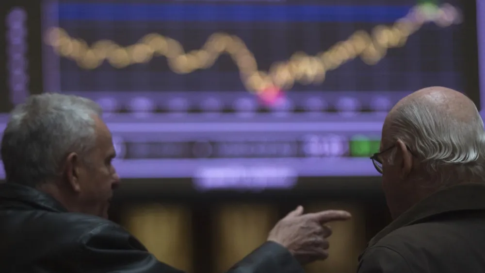 Traders talk in front of a screen showing an index at Madrid's Bourse February 14, 2012. European shares fell on Tuesday after rating agency Moody's put the United Kingdom's triple-A rating in jeopardy for the first time and warned it may cut France and Austria as well, while downgrading six euro zone nations including Spain and Italy. REUTERS/Sergio Perez (SPAIN - Tags: BUSINESS)