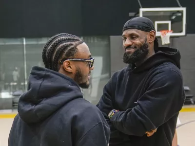 Los Angeles Lakers draft pick Bronny James, left, and his father, LeBron James, share a light moment as they arrive for the NBA basketball team's news conference in El Segundo, Calif., Tuesday, July 2, 2024 (AP Photo/Damian Dovarganes)