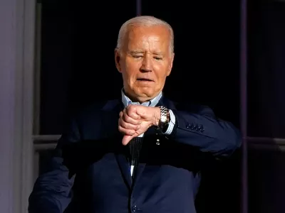 U.S. President Joe Biden looks at his watch as he stands on the balcony during an Independence Day celebration on the South Lawn of the White House in Washington, U.S., July 4, 2024. REUTERS/Elizabeth Frantz