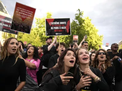 People react to the projection of results during the second round of the legislative elections, near Republique Plaza in Paris, France. Polls have closed in France, and polling projections say a coalition on the left that came together unexpectedly has won the most parliamentary seats in the pivotal runoff elections after a high turnout among voters. Sign reads "The extreme right shall not pass. From Gaza to Paris Intifada". (AP Photo/Christophe Ena)