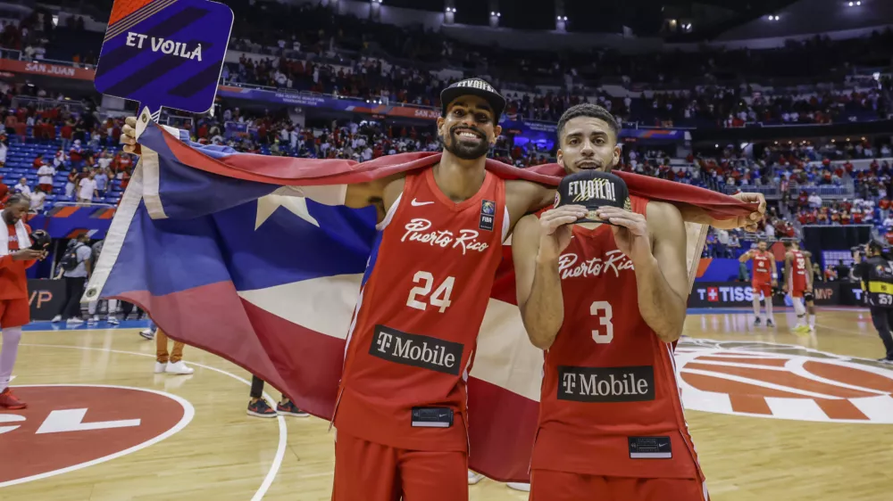 Puerto Rico's Jordan Howard, right, and Gian Clavell celebrate after their team qualified for the Paris 2024 Olympics, after eliminating Lithuania in a FIBA Olympic Qualifying basketball final in San Juan, Puerto Rico, Sunday, July 7, 2024. (AP Photo/Alejandro Granadillo)