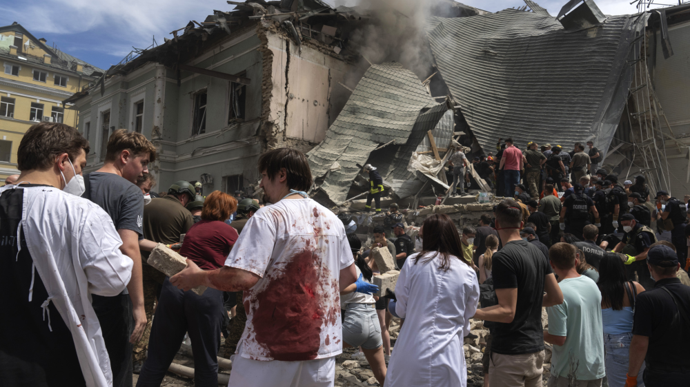 Rescuers, volunteers and medical workers, some in bloodied uniforms clean up the rubble and search victims after Russian missile hit the country's main children hospital Okhmadit, in Kyiv, Ukraine, Monday, July 8, 2024. A major Russian missile attack across Ukraine killed at least 20 people and injured more than 50 on Monday, officials said, with one missile striking a large children's hospital in the capital, Kyiv, where emergency crews searched rubble for casualties. (AP Photo/Efrem Lukatsky)