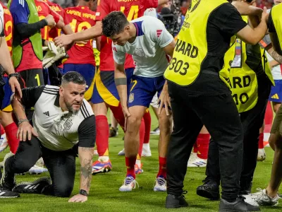 Spain's Alvaro Morata, centre, holds his leg after an incident with an invader after a semifinal match between Spain and France at the Euro 2024 soccer tournament in Munich, Germany, Tuesday, July 9, 2024. Left Spain's Rodri. (AP Photo/Hassan Ammar)