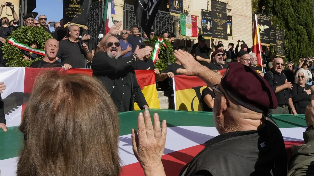 People perform a roman salute in the hometown of former dictator Benito Mussolini to mark the 100th anniversary of the coup d'etat by which he sized power in 1922, in Predappio, Italy, Sunday, Oct. 30, 2022. (AP Photo/Luca Bruno)