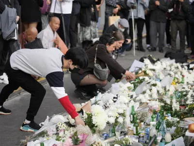 Mourners place flowers to pay tribute for victims of a deadly accident following Saturday night's Halloween festivities on a street near the scene in Seoul, South Korea, Monday, Oct. 31, 2022. A crowd surge killed more than 150 people during Halloween festivities in Seoul over the weekend in the country's worst disasters in years. (AP Photo/Lee Jin-man)