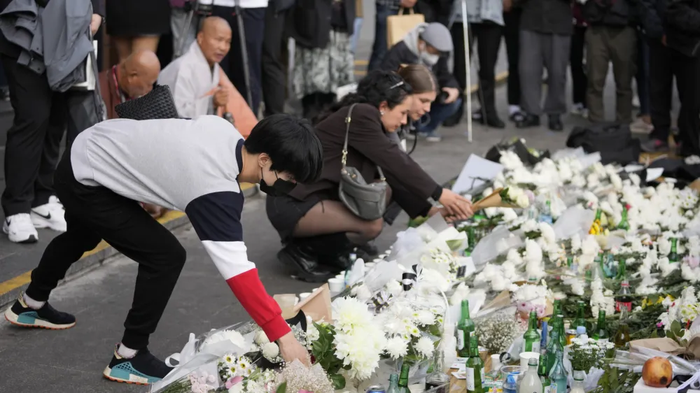 Mourners place flowers to pay tribute for victims of a deadly accident following Saturday night's Halloween festivities on a street near the scene in Seoul, South Korea, Monday, Oct. 31, 2022. A crowd surge killed more than 150 people during Halloween festivities in Seoul over the weekend in the country's worst disasters in years. (AP Photo/Lee Jin-man)