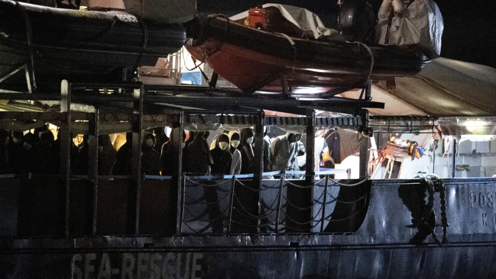 Migrants stand on the deck of the Humanity 1 rescue ship run by the German organization SOS Humanitarian, at harbor in the port of Catania, Sicily, southern Italy, early Sunday, Oct. 6, 2022. Italy allowed the Humanity 1 rescue ship carrying over 100 migrants to enter the Sicilian port and begin disembarking minors, while refusing to respond to requests for safe harbor from three other ships carrying 900 more people in nearby waters. (AP Photo/Salvatore Cavalli)