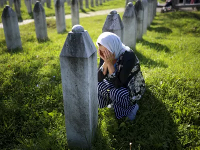 A Bosnian Muslim woman mourns next to the grave of her relative, victim of the Srebrenica genocide, at the Srebrenica Memorial Centre, in Potocari, Bosnia, Thursday, July 11, 2024. Thousands gathered in the eastern Bosnian town of Srebrenica to commemorate the 29th anniversary on Monday of Europe's only acknowledged genocide since World War II. (AP Photo/Armin Durgut)