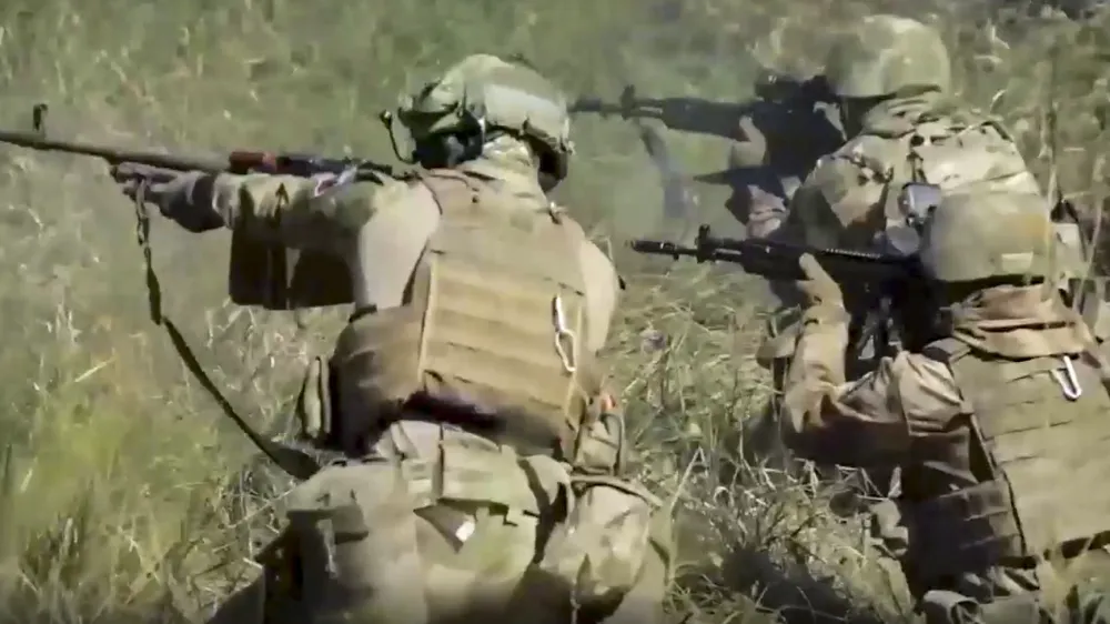 FILE - In this handout photo taken from video released by Russian Defense Ministry Press Service on Sept. 19, 2022, members of a special forces unit of the Russian army aim their weapons in action at an unspecified location in Ukraine. Even as the Kremlin moved to absorb four Ukrainian regions in a sharp escalation of the conflict, the Russian military suffered new stinging defeats that highlighted its deep problems.(Russian Defense Ministry Press Service via AP, File)