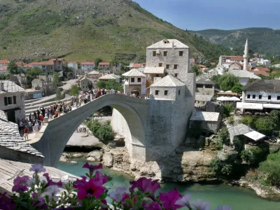 Tourists pass over the recently rebuilt Mostar Old Bridge, Monday, Aug. 16, 2004. According to authorities, some 150,000 tourists have visited the newly rebuilt Mostar Bridge in the last two months. The over 400-year-old bridge was destroyed during the 1992-95 Bosnian war but then was rebuilt and re-opened this summer. Builders used old building techniques and original parts of the old bridge, which were extracted from the river Neretva.(AP Photo/Hidajet Delic)