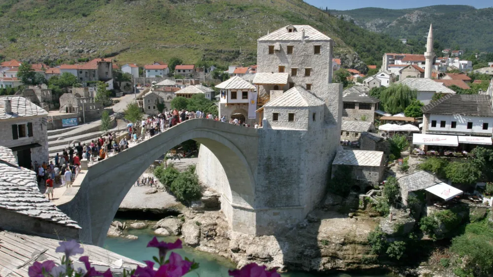 Tourists pass over the recently rebuilt Mostar Old Bridge, Monday, Aug. 16, 2004. According to authorities, some 150,000 tourists have visited the newly rebuilt Mostar Bridge in the last two months. The over 400-year-old bridge was destroyed during the 1992-95 Bosnian war but then was rebuilt and re-opened this summer. Builders used old building techniques and original parts of the old bridge, which were extracted from the river Neretva.(AP Photo/Hidajet Delic)