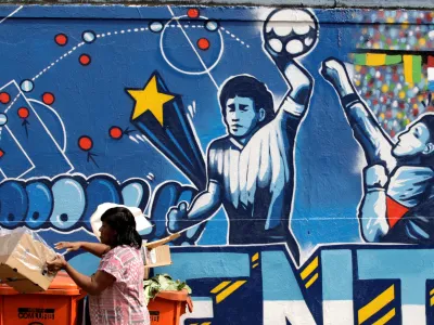 FILE PHOTO: A resident stands near a mural depicting the famous "Hand of God" goal by former Argentine soccer star Diego Maradona, in light of the upcoming 2010 FIFA World Cup at the Agua Santa neighborhood in Rio de Janeiro May 21, 2010. REUTERS/Sergio Moraes/File Photo