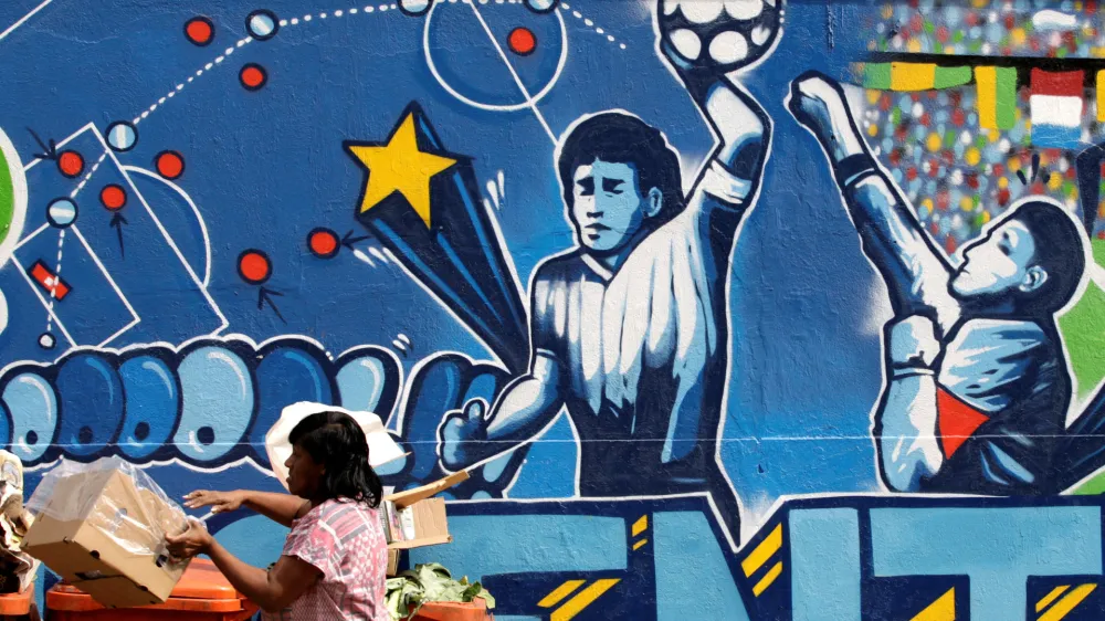 FILE PHOTO: A resident stands near a mural depicting the famous "Hand of God" goal by former Argentine soccer star Diego Maradona, in light of the upcoming 2010 FIFA World Cup at the Agua Santa neighborhood in Rio de Janeiro May 21, 2010. REUTERS/Sergio Moraes/File Photo