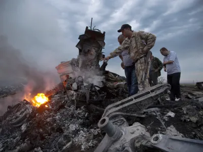 FILE - People inspect the crash site of a passenger plane near the village of Grabovo, Ukraine, on July 17, 2014. A Dutch court on Thursday is set to deliver verdicts in the long-running trial of three Russians and a Ukrainian rebel for their alleged roles in the shooting down of Malaysia Airlines flight MH17 over conflict-torn eastern Ukraine. (AP Photo/Dmitry Lovetsky, File)