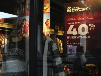 The reflections of passing shoppers are seen in the glass of a Hollister clothing store advertising sales, ahead of Black Friday and the Thanksgiving holiday, Monday, Nov. 21, 2022, in Miami. Retailers are ushering in the start of the holiday shopping season on the day after Thanksgiving, preparing for the biggest crowds since 2019. (AP Photo/Rebecca Blackwell)