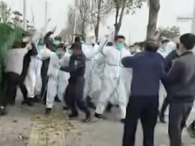 In this photo provided Nov 23, 2022, security personnel in protective clothing attack a man during protest at the factory compound operated by Foxconn Technology Group who runs the world's biggest Apple iPhone factory in Zhengzhou in central China's Henan province. Employees at the world's biggest Apple iPhone factory were beaten and detained in protests over pay amid anti-virus controls, according to witnesses and videos on social media Wednesday, as tensions mount over Chinese efforts to combat a renewed rise in infections. (AP)