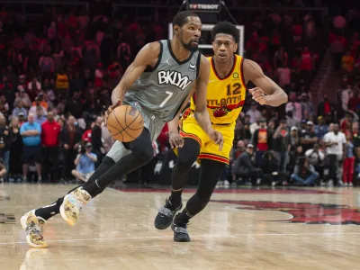 Brooklyn Nets forward Kevin Durant (7) dribbles past Atlanta Hawks forward De'Andre Hunter (12) during the second half of an NBA basketball game Saturday, April 2, 2022, in Atlanta. (AP Photo/Hakim Wright Sr.)