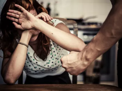 DFMBNE Young woman covering her face in fear of domestic violence