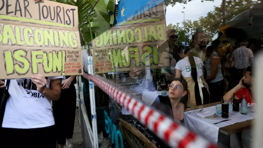 A tourist watches as demonstrators protest against mass tourism in Barcelona, Spain, July 6, 2024. The Catalan capital received more than 12 million tourists in 2023 and expects more in 2024. REUTERS/Bruna Casas / Foto: Bruna Casas