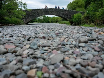 People cross a bridge over the dry river bed of the River Derwent after a prolonged period of dry weather in Grange, Britain, June 18, 2023. REUTERS/Phil Noble   TPX IMAGES OF THE DAY