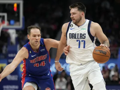 Dallas Mavericks guard Luka Doncic (77) brings the ball up court as Detroit Pistons forward Bojan Bogdanovic (44) defends during the second half of an NBA basketball game, Thursday, Dec. 1, 2022, in Detroit. (AP Photo/Carlos Osorio)