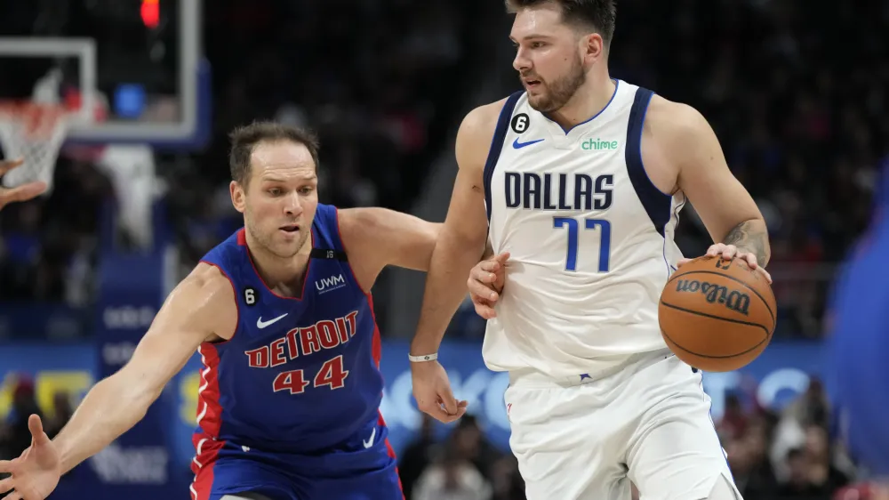 Dallas Mavericks guard Luka Doncic (77) brings the ball up court as Detroit Pistons forward Bojan Bogdanovic (44) defends during the second half of an NBA basketball game, Thursday, Dec. 1, 2022, in Detroit. (AP Photo/Carlos Osorio)