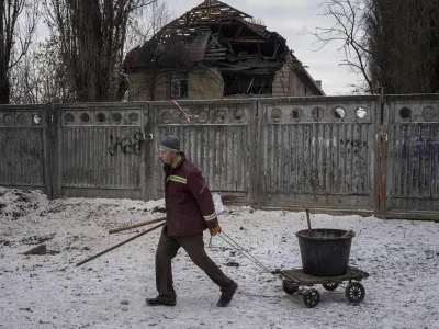 A municipal worker walks in front of a tax office building that have been heavily damaged by a Russian attack in Kyiv, Ukraine, Wednesday, Dec. 14, 2022. (AP Photo/Evgeniy Maloletka)