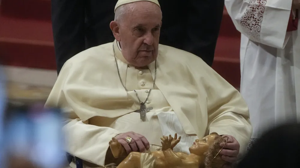 Pope Francis holds a statue of Baby Jesus as he presides over Christmas Eve Mass, at St. Peter's Basilica at the Vatican, Saturday Dec. 24, 2022. (AP Photo/Gregorio Borgia)