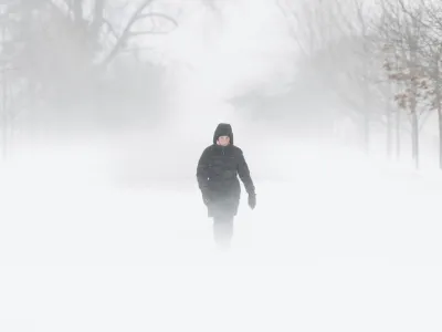 A person walks through the Central Experimental Farm during strong winds and snow squalls in Ottawa, Canada, on Saturday, Dec. 24, 2022. Environment Canada has issued a winter storm warning for the region. (Spencer Colby/The Canadian Press via AP)