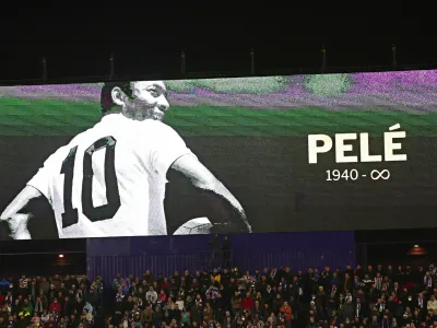 Fans sit beneath a giant screen during a minute of silence for Pelé before the start of a Spanish La Liga soccer match between Valladolid and Real Madrid at the Jose Zorrilla stadium in Valladolid, Spain, Friday, Dec. 30, 2022. Pelé, the Brazilian king of soccer who won a record three World Cups and became one of the most commanding sports figures of the last century, died in Sao Paulo on Thursday. He was 82. (AP Photo/Pablo Garcia)