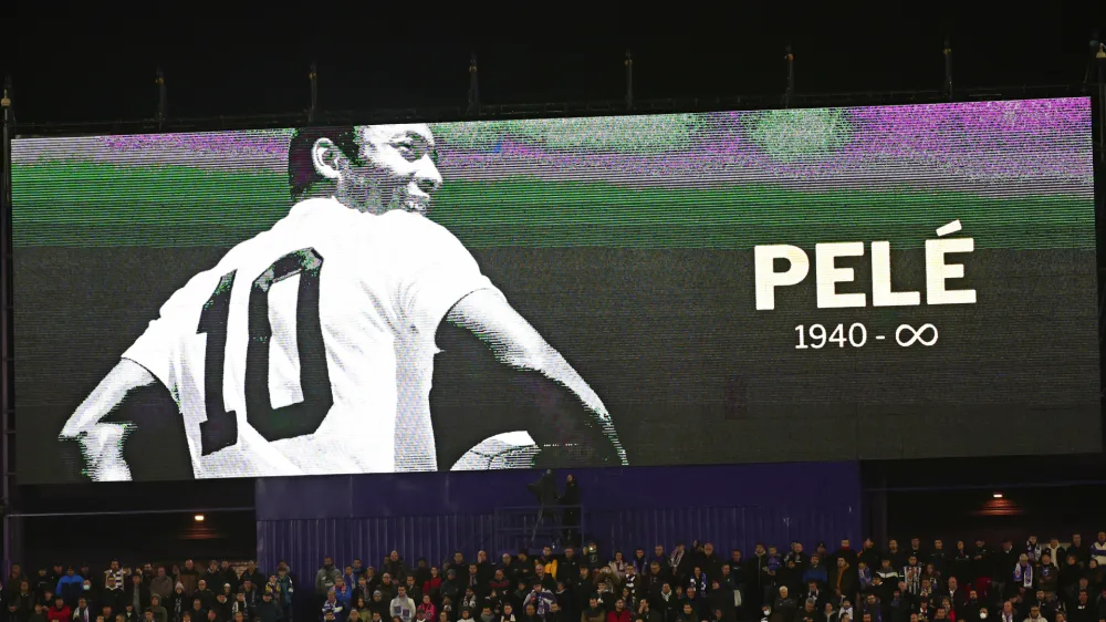 Fans sit beneath a giant screen during a minute of silence for Pelé before the start of a Spanish La Liga soccer match between Valladolid and Real Madrid at the Jose Zorrilla stadium in Valladolid, Spain, Friday, Dec. 30, 2022. Pelé, the Brazilian king of soccer who won a record three World Cups and became one of the most commanding sports figures of the last century, died in Sao Paulo on Thursday. He was 82. (AP Photo/Pablo Garcia)