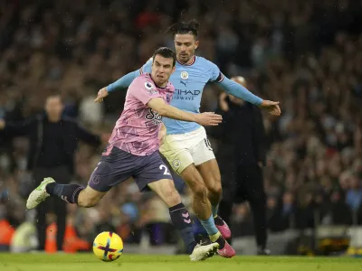 Everton's Seamus Coleman, left, challenges Manchester City's Jack Grealish during the English Premier League soccer match between Manchester City and Everton at the Etihad Stadium in Manchester, England, Saturday, Dec. 31, 2022. (AP Photo/Dave Thompson)