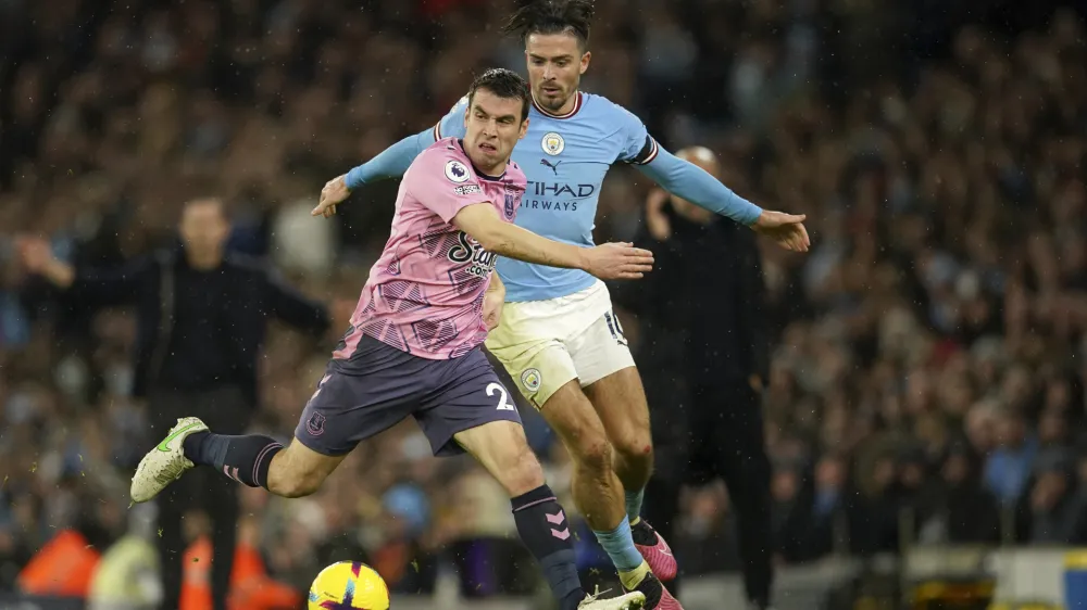 Everton's Seamus Coleman, left, challenges Manchester City's Jack Grealish during the English Premier League soccer match between Manchester City and Everton at the Etihad Stadium in Manchester, England, Saturday, Dec. 31, 2022. (AP Photo/Dave Thompson)