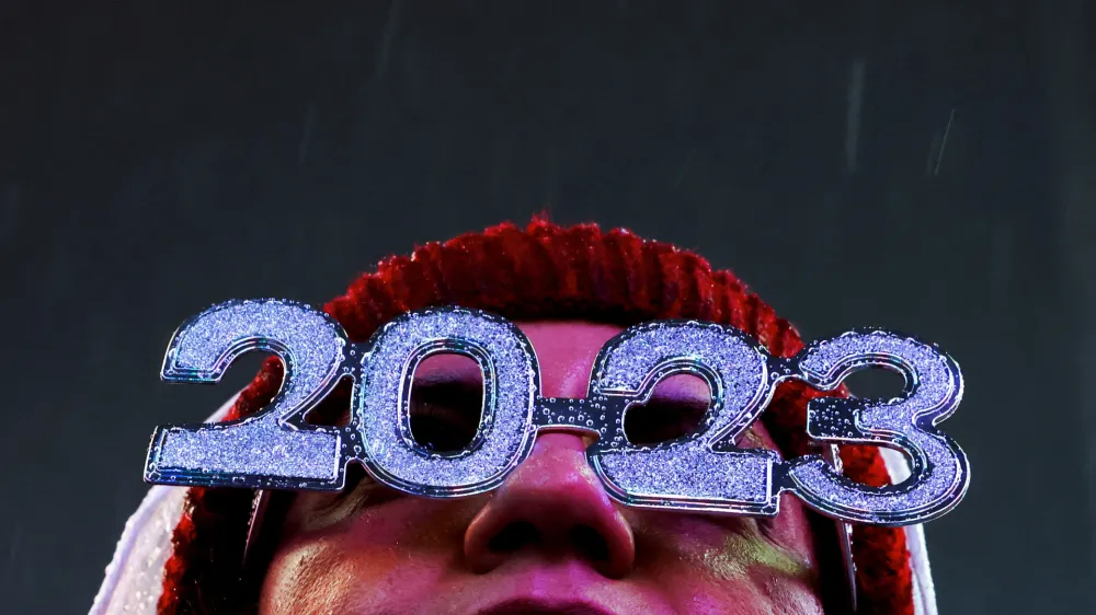 A reveller wearing glasses stands in the rain in Times Square during the first New Year's Eve event without restrictions since the coronavirus disease (COVID-19) pandemic in the Manhattan borough of New York City, New York, U.S., December 31, 2022. REUTERS/Andrew Kelly - RC2DHY9508FG