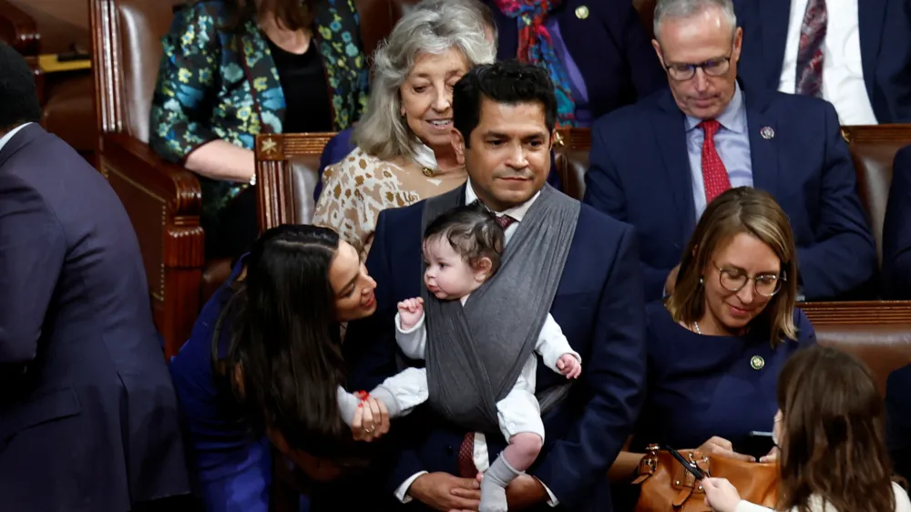 U.S. Rep. Alexandria Ocasio-Cortez (D-NY) talks to the infant child of Rep. Jimmy Gomez (D-CA) inside the House Chamber during votes for the next Speaker of the House on the first day of the 118th Congress at the U.S. Capitol in Washington, U.S., January 3, 2023. REUTERS/Evelyn Hockstein